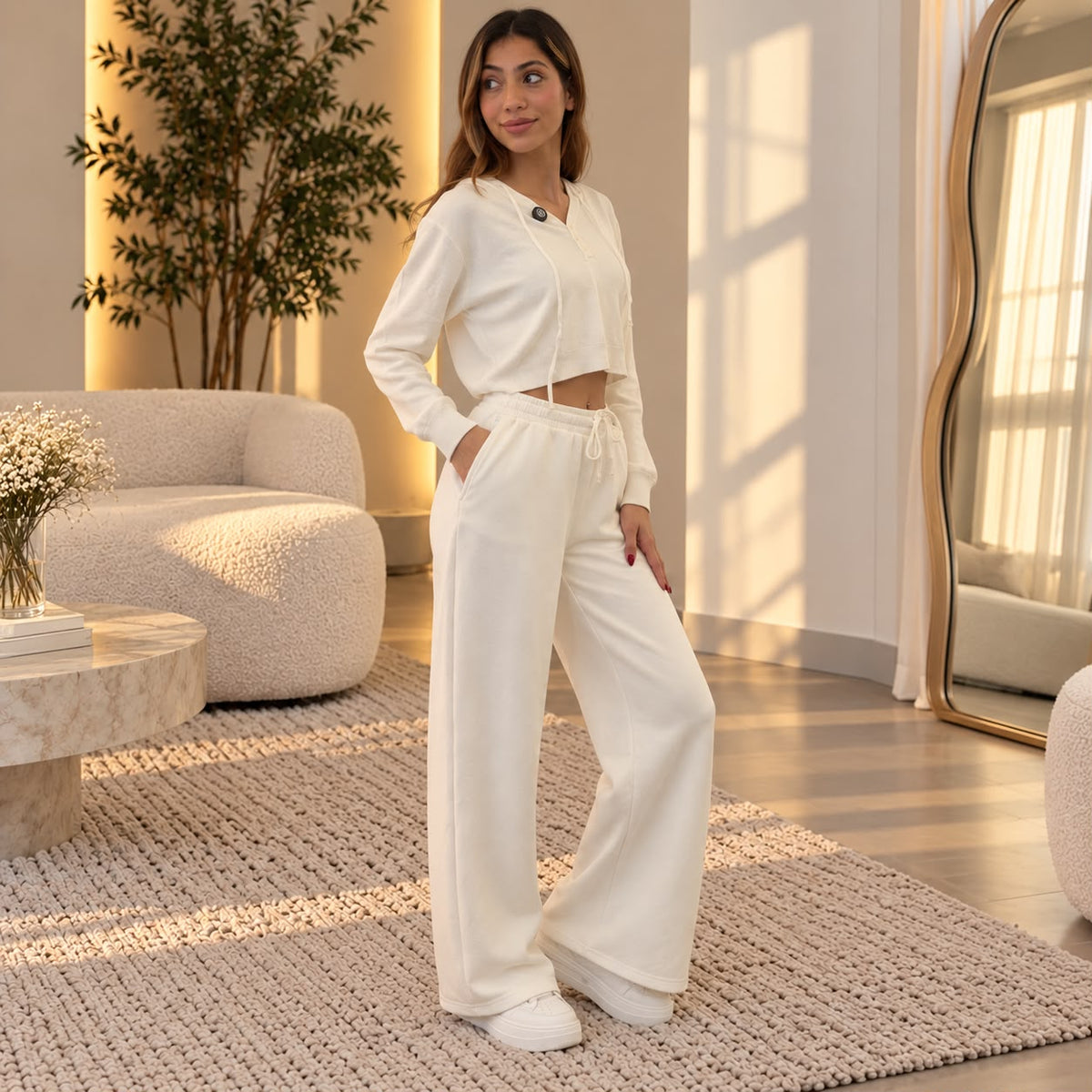 Woman in white wide leg sweatpants and a matching cropped top, hand in her pocket