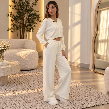 Woman in white wide leg sweatpants and a matching cropped top, hand in her pocket
