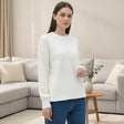 Plain white long sleeve wool top in fine knit, worn in a living room setting