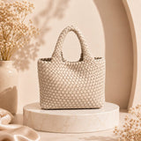 white Woven handbag on a round platform with a vase and dried flowers in the background, price tag '20$' displayed.