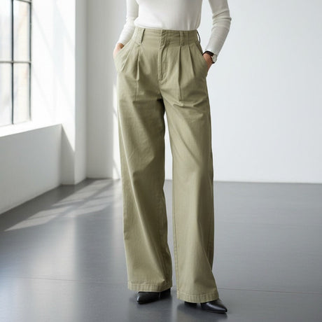 Woman wearing a white top and wide-leg pants in a minimalistic room