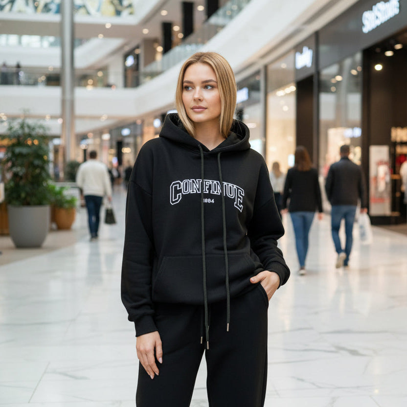 Woman wearing a black hoodie and sweatpants in a shopping mall