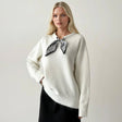 White fluffy jumper with a black and silver print scarf knotted at the collar