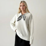 White fluffy jumper with a black and silver print scarf knotted at the collar