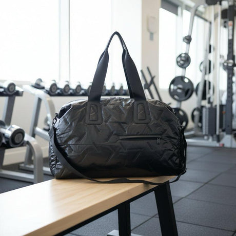Black duffel bag on a wooden bench in a gym setting