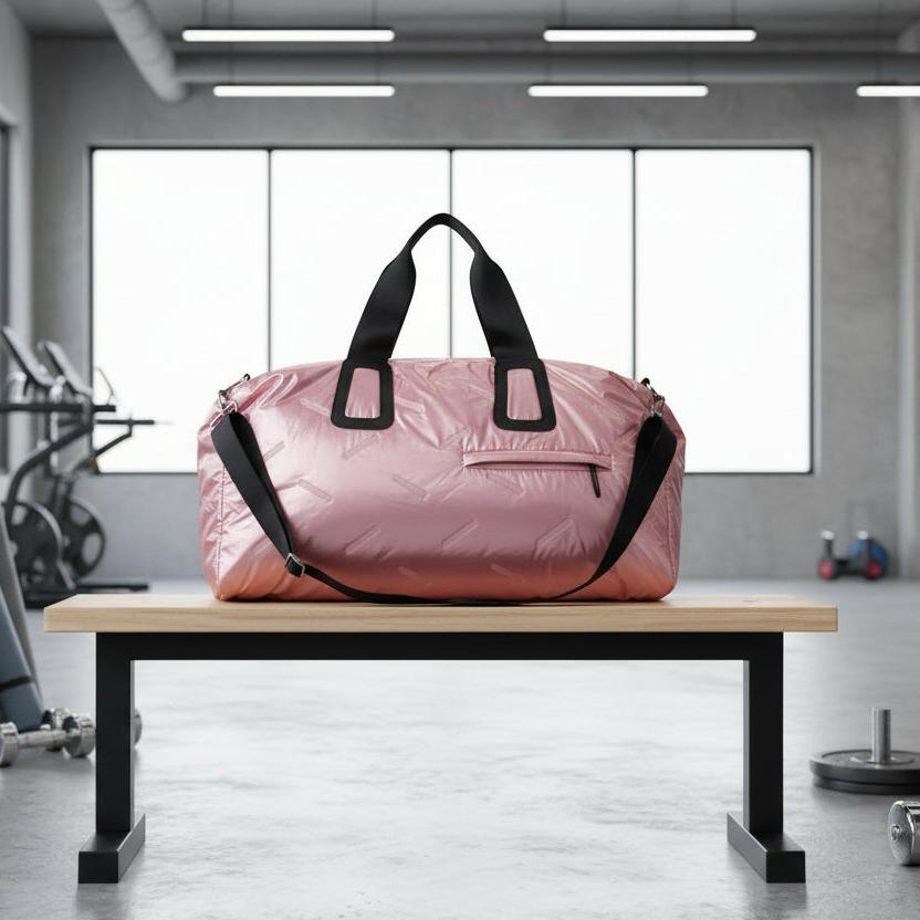 Pink duffel bag with black straps on a wooden bench in a gym setting