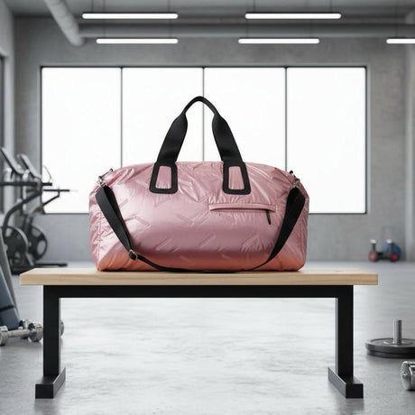 Pink duffel bag with black straps on a wooden bench in a gym setting