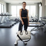 Woman holding a white gym duffle bag in a gym setting