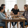 Four friends playing chess on a wooden board at a rustic dining table