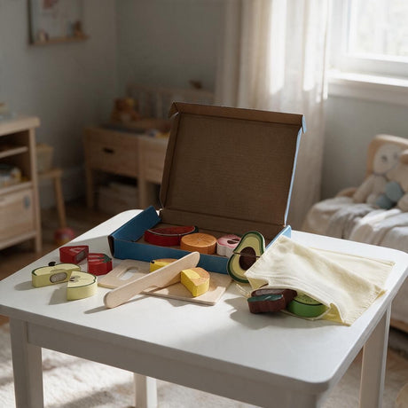 Fruit cutting set with wooden apple, avocado and melon slices, a board and knife on a white table