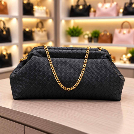 Black woven clutch bag seen at a slight angle with its gold chain strap draped over the front