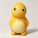 Yellow dinosaur squishy with green eyes, a little frown and a cream belly, front view