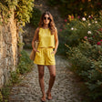 Woman in a yellow outfit walking along a stone path in a garden