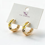 Pair of chunky gold tone C hoops with yellow enamel flowers on a white display card