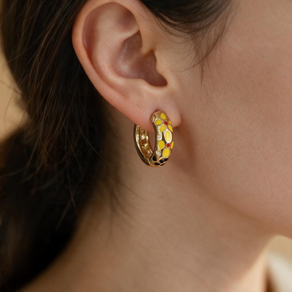 Yellow flower enamel open hoop earring with red and black accents worn on the ear