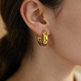 Yellow flower enamel open hoop earring with red and black accents worn on the ear