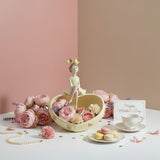 The yellow heart dish filled with pink roses beside macarons and a teacup