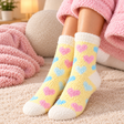 Fuzzy yellow kids socks with pink and blue hearts and white cuffs, toes and heels