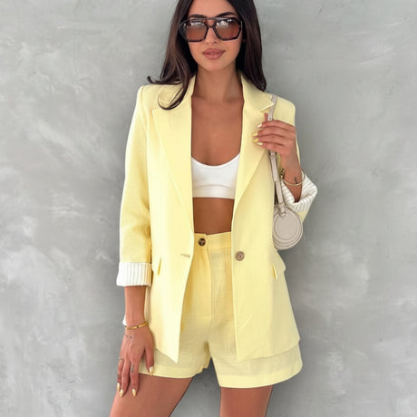Woman wearing a yellow linen outfit with text detailing item prices on a gray background