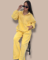 Person wearing a yellow tracksuit sitting on a chair against a beige background
