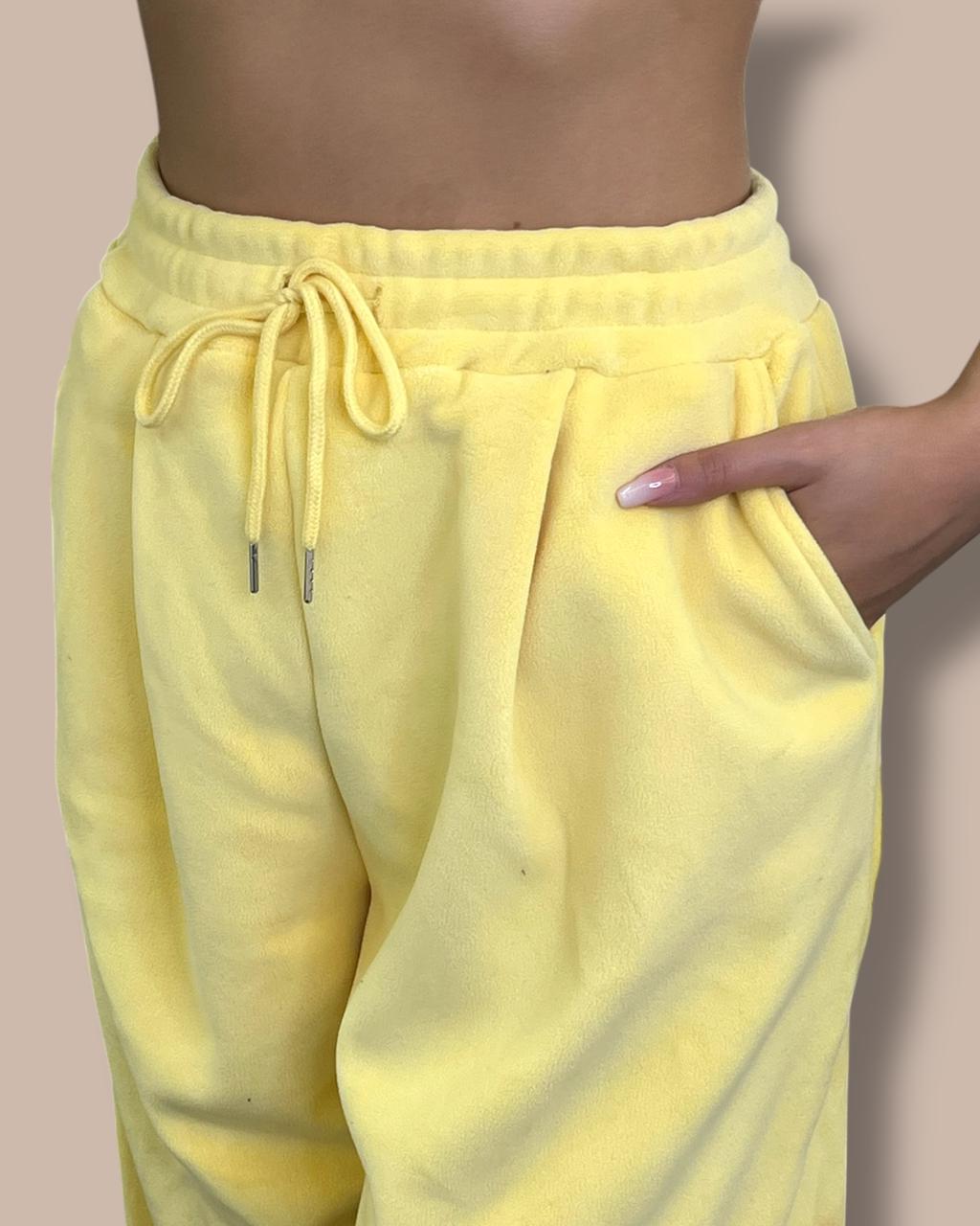 Yellow sweatpants worn by a person on a beige background