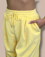 Yellow sweatpants worn by a person on a beige background