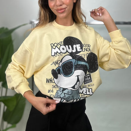 Woman in a soft yellow MickeyMouse sweatshirt with rhinestone details and black pants