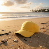 Yellow cotton summer cap on a shell scattered beach at golden hour