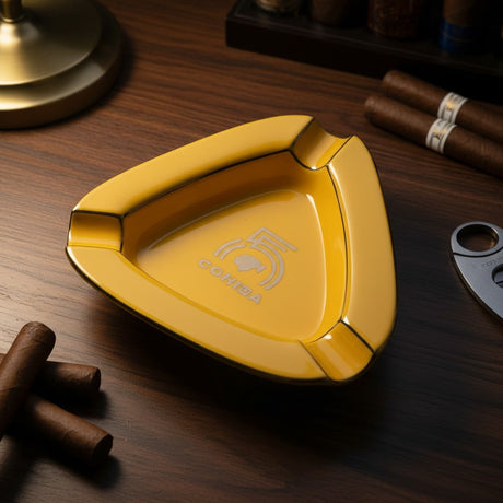 Yellow triangle ceramic cigar ashtray with three corner rests and a thin gold rim