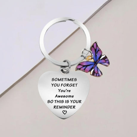 Engraved heart keychain with a purple enamel butterfly charm, close view of the message