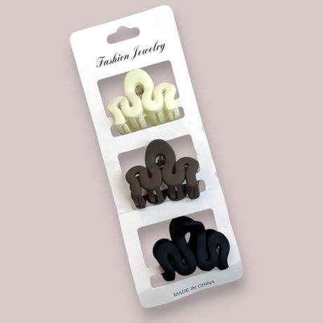 Three matte squiggle wave claw clips in ivory, brown and black on a retail display card