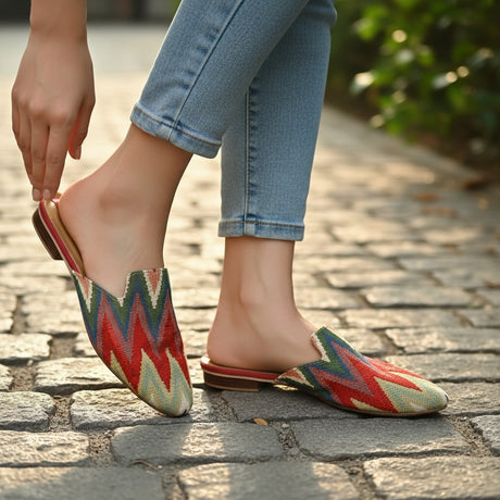 Red, green and cream zigzag handmade mules worn with cuffed jeans on cobblestones