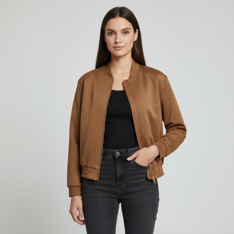 Woman wearing a brown jacket over a black top and jeans on a light grey background