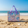 Colorful transparent bag with cartoon cat designs on a beach