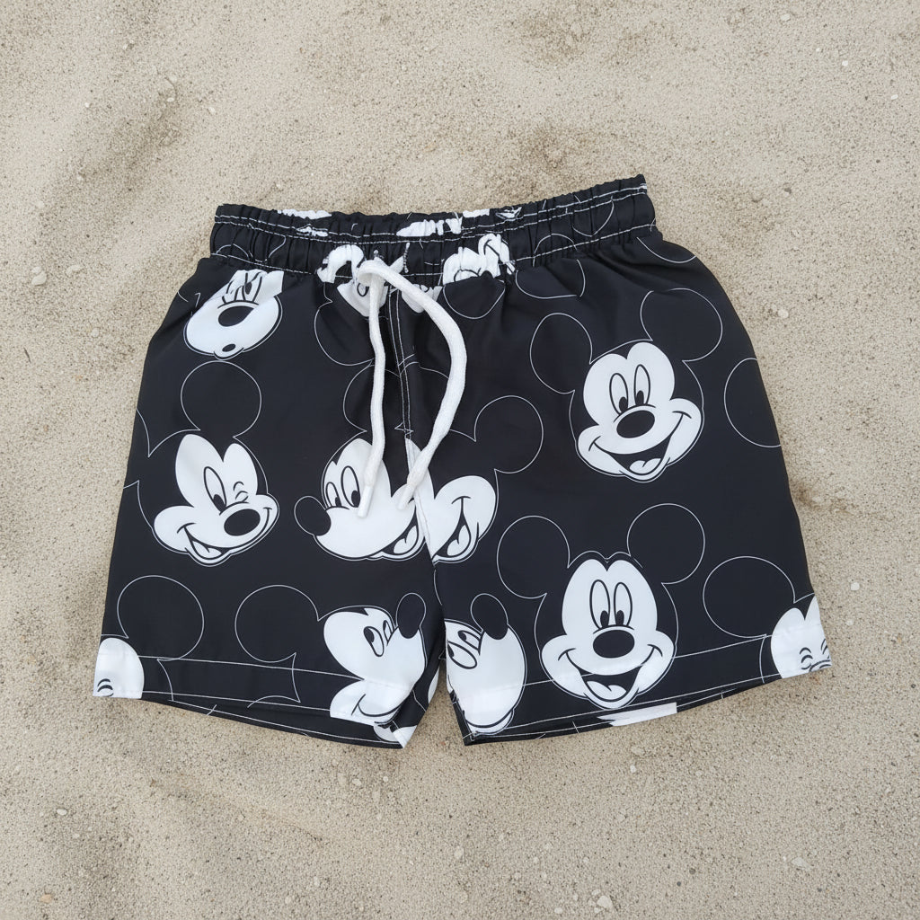 Black shorts with white Mickey Mouse faces on a gray floor.