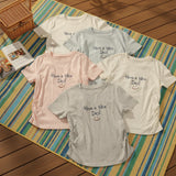 Five t-shirts with 'Have a Nice Day!' text on a striped mat.