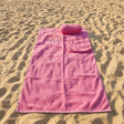 Pink towel with embroidered text on a dark surface