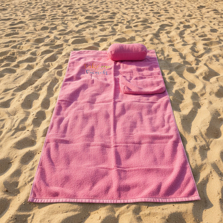 Pink towel with embroidered text on a dark surface