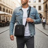 Man wearing a navy crossbody bag in an urban setting