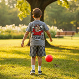 Child playing with a red ball in a park with a large tree in the background