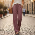 Person wearing a white top and mauve pants walking on a cobblestone street.