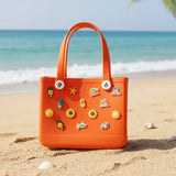 Orange crocs bag with colorful pins on the sand.