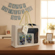Gift set with 'Super Dad' t-shirts in a white box on a table with 'Happy Father's Day' banner in the background.