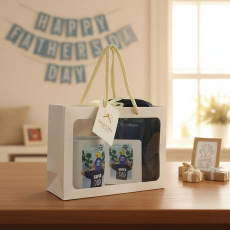 Gift set with 'Super Dad' t-shirts in a white box on a table with 'Happy Father's Day' banner in the background.