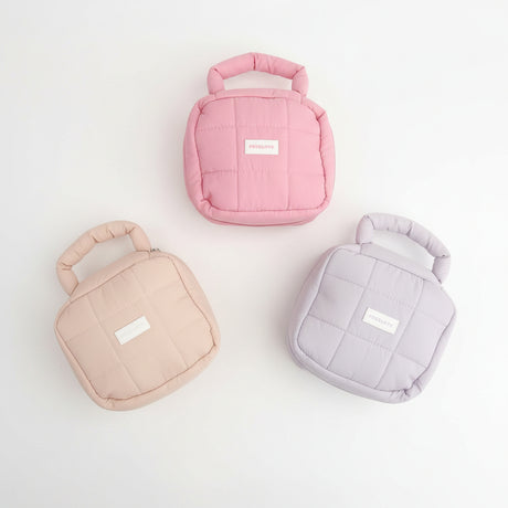 Three small quilted bags in pink, beige, and purple on a gray surface.
