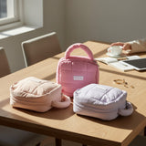 Pink and white cat-shaped bags on a wooden table with a person holding a cup in the background.