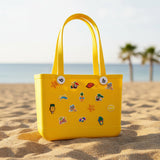 Yellow children's crocs bag with various pins on teh beach.